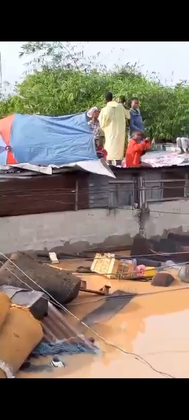 Des familles, dont des femmes et des enfants, réfugiées sur un toit de fortune à Kinshasa après de fortes inondations, sans abri ni assistance